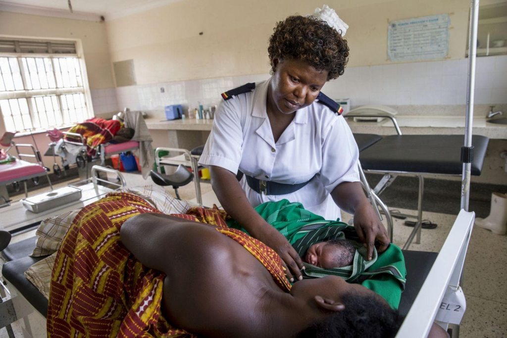 Eine Krankenschwester untersucht in einer Klink in Uganda eine Mutter und ihr neugeborenes Kind